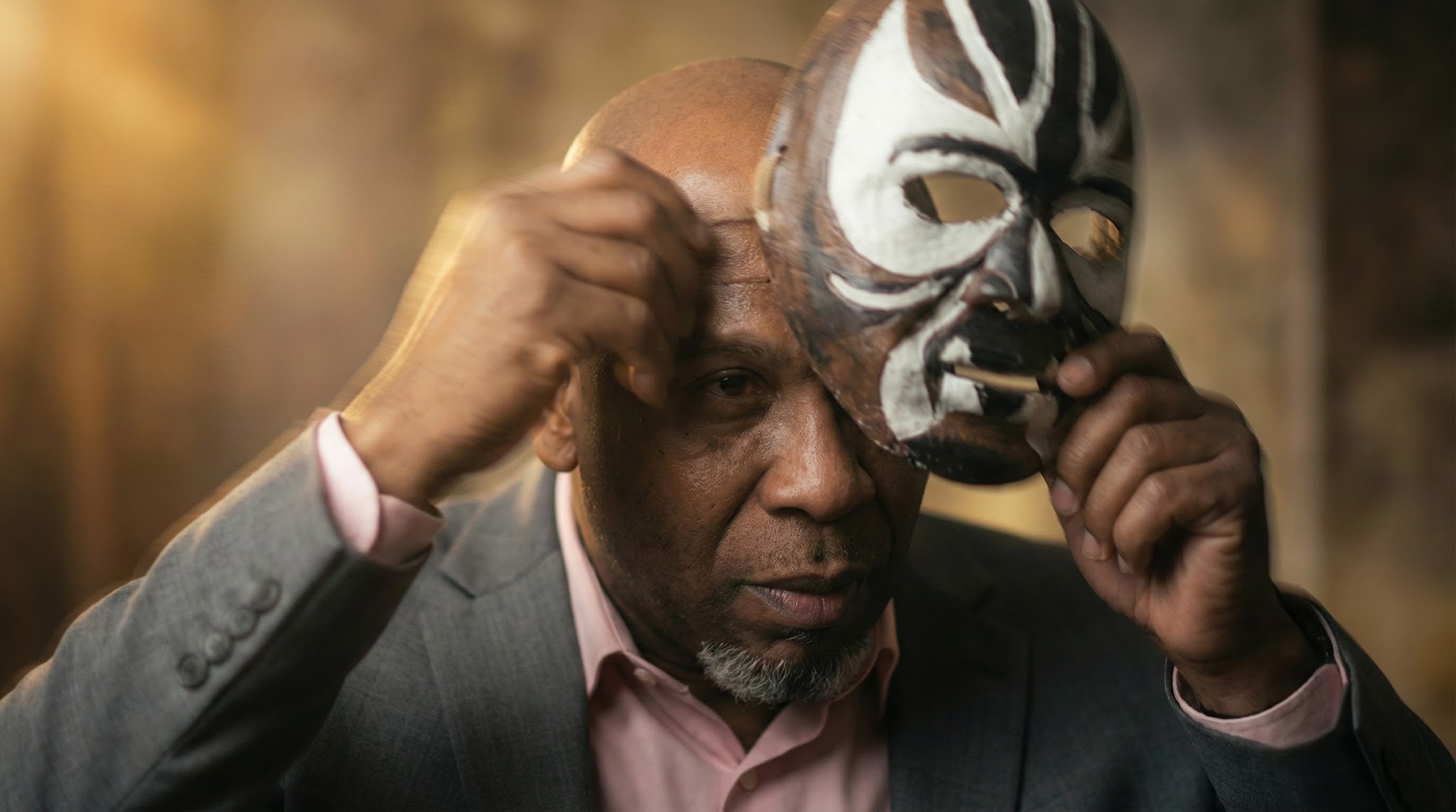 Pastor James E. Radford lifting a wrestling mask to reveal his face
